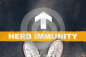 Herd immunity written on yellow line with white arrow on asphalt road