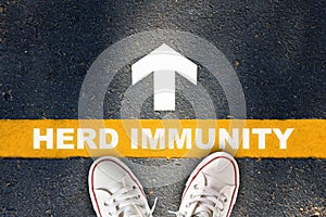 Herd immunity written on yellow line with white arrow on asphalt road photo