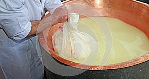 Herdsman Cheesemaker collects cheese from the copper cauldron w