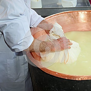 herdsman Cheesemaker collects cheese from the copper cauldron w