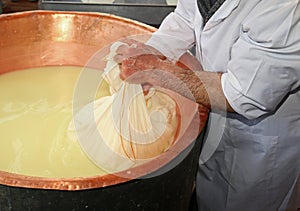 herdsman Cheesemaker collects cheese from the copper cauldron w