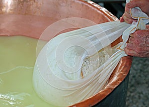 herdsman Cheesemaker collects cheese from the copper cauldron w