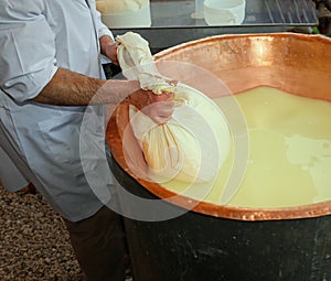 Herdsman Cheesemaker collects cheese from the copper cauldron w