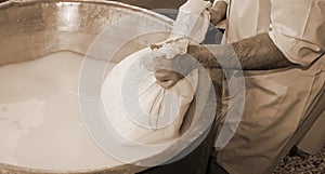 Herdsman Cheesemaker collects cheese from the copper cauldron wi