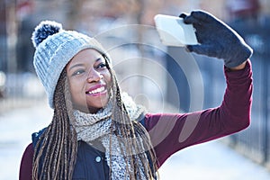 Here comes the snowand the selfies. a beautiful young woman taking a selfie on a snowy day outdoors.
