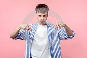 Here and right now. Portrait of angry bossy brown-haired man with small beard and mustache pointing down. isolated on pink