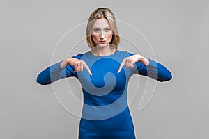 Here and right now. Portrait of bossy businesswoman pointing fingers down. isolated on gray background