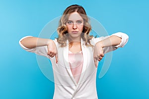 Here and right now! Portrait of strict serious woman boss pointing down with angry face. isolated on blue background