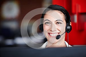 Always here to help. Portrait of a pretty call center agent wearing a headset and sitting in front of her computer.