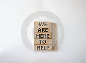 We are here to help symbol. Concept words we are here to help on wooden blocks. Beautiful white background. Business and we are
