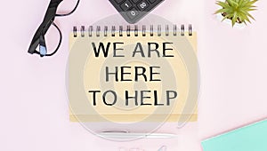 We are here to help, is written on a notepad