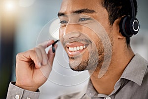 Here to help you fight the blues. a young male call center agent on a call with a customer at his desk.