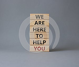 We are here to help you symbol. Concept words we are here to help you on wooden blocks. Beautiful grey background. Business and we