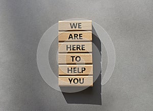 We are here to help you symbol. Concept words we are here to help you on wooden blocks. Beautiful grey background. Business and we