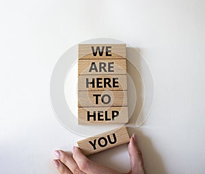 We are here to help you symbol. Concept words we are here to help you on wooden blocks. Beautiful white background. Businessman
