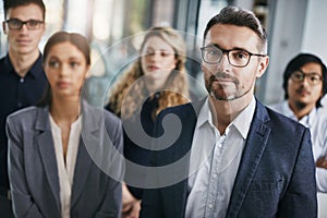 Here to surpass expectations. Portrait of a mature businessman standing in an office with his colleagues in the