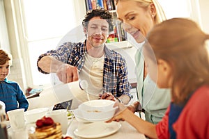 Here you go, my angel. a family enjoying breakfast together at home.