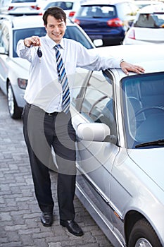 Here are your car keys. A happy car salesman handing you the keys to your new car.