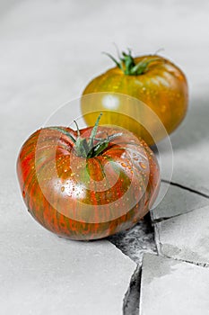 Hereditary tomatoes. Two tomatoes of different colors on a gray concrete table with a crack