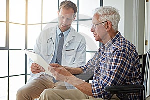 Heres the prognosis. a male doctor talking to a senior patient in the retirement home.