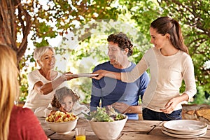 Heres some for you grandma. A view of a family preparing to eat lunch together outdoors.