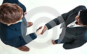 Heres to business success. High angle shot of two businesspeople shaking hands in an office.