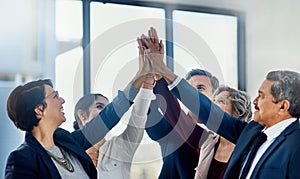Heres to a job well done. Cropped shot of a group of happy businesspeople giving each other a high five in the office.
