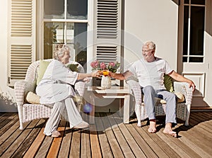 Heres to more mornings like this. Shot of a happy senior couple toasting with juice on the patio at home.