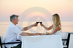 Heres to us. Shot of a mature couple enjoying a romantic dinner on the beach.