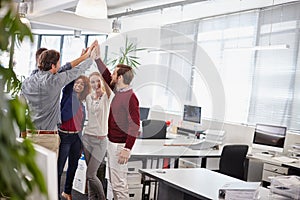 Heres to us. a team of businesspeople giving each other a high five in the office.