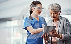 Heres your full medical history. a young female nurse and her senior patient looking at a tablet in the old age home.