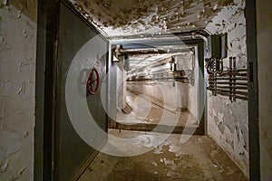 Hermetic rusty door of the bunker in underground abandoned tunnel. Mysterious old iron gate. Secret entrance