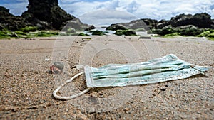 A hermit crab near medical waste, masks garbage trash on sea water. Covid-19