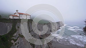 Hermitage of San Telmo with the Dragonstone cave located below it on a foggy day in Zumaia, Basque Country