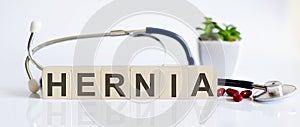 HERNIA the word is written on wooden cubes and sthetoscope and piils . Medicine