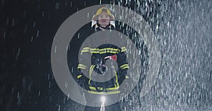 Hero shot, portrait of tired American female firefighter standing taking off her protective helmet, looking into camera