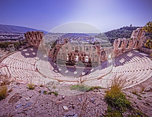 Herodium ancient open theater under acropolis and panoramic view of Athens city under crystal clear blue sky.