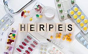 HERPES medicine word on wooden blocks on a desk. Medical concept with pills, vitamins, stethoscope and syringe on the background