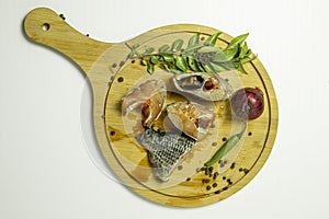 Herring fillet with herbs and spices on a wooden board. Top view
