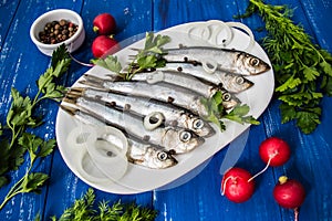 Herring fish with greens on a wooden blue background. Top view. Close-up