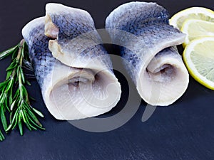 Herring rolls with chives and lemon serwed on dark background