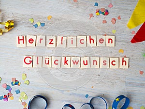 Herzlichen GlÃ¼ckwunsch congratulations lettering with party supplies on wooden background