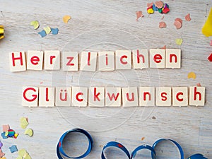 Herzlichen GlÃ¼ckwunsch congratulations lettering with party supplies on wooden background