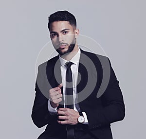 Hes all about business. Studio shot of a young man posing against a grey background.