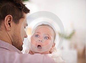 Hes an amazing father. A cute baby girl looking over her fathers shoulder as he holds her.