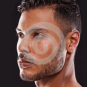 Hes the brains and the brawn. Studio shot of a handsome young man against a black background.