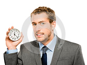 Hes always on the clock. a businessman holding a clock against a studio background.