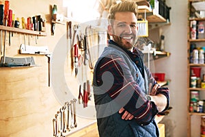 Hes a confident craftsman. Portrait of a handsome young handyman standing with his arms folded in a workshop.