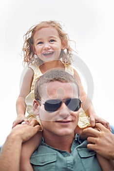 Hes the cool dad. Portrait of a young father wearing sunglasses while carrying his daughter on his shoulders.