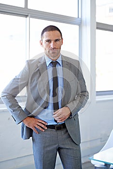 Hes a corporate heavyweight. a handsome businessman standing in his office.